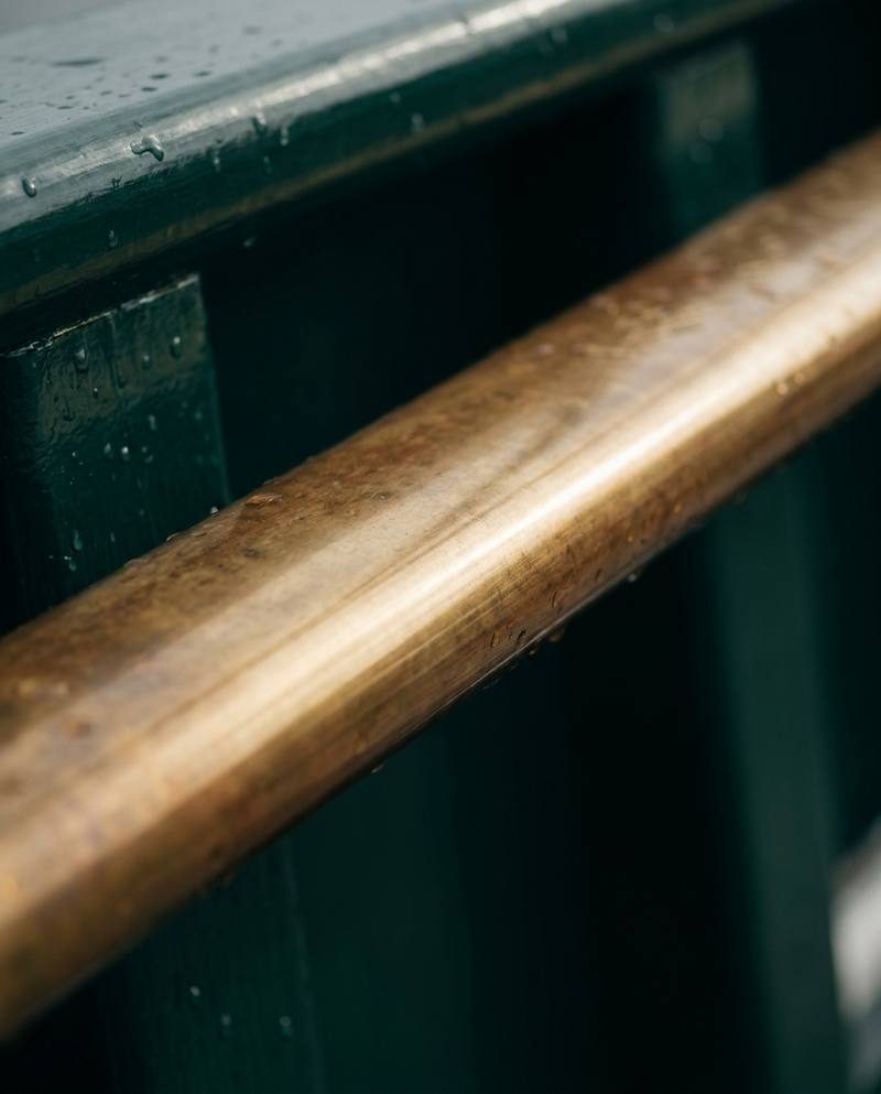 Polished brass rail on green painted wood